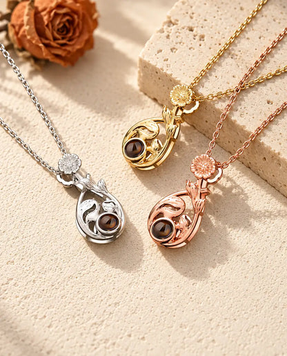 Silver tone, gold tone and rose gold tone daisy teardrop pendants on travertine