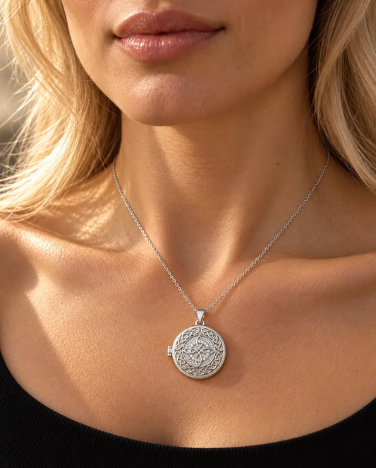Woman in a black knit top wearing the silver tone four-loop Celtic knot photo locket necklace