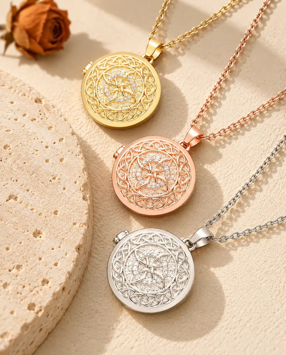 Gold tone, rose gold tone and silver tone four-loop Celtic knot photo lockets stacked beside a travertine slab