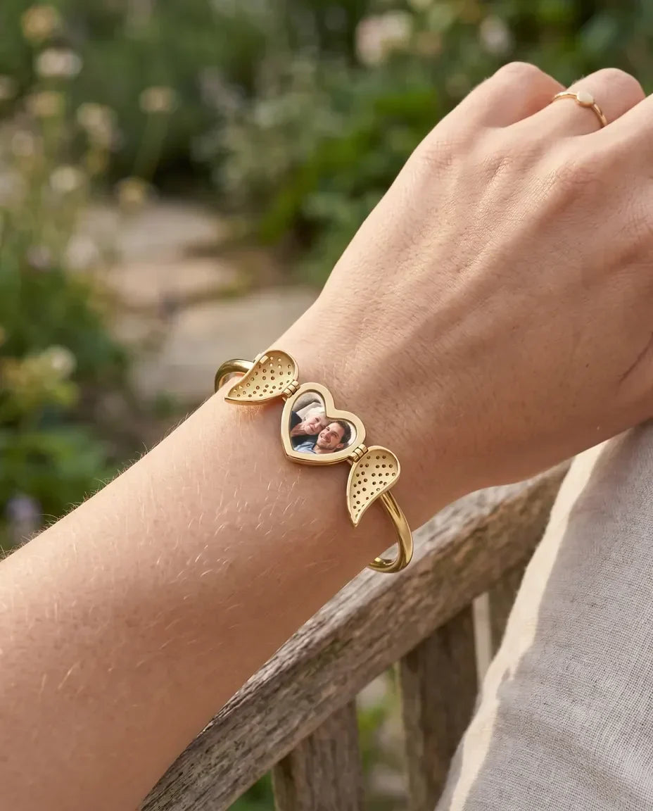 Woman wearing gold angel wing heart photo bangle outdoors
