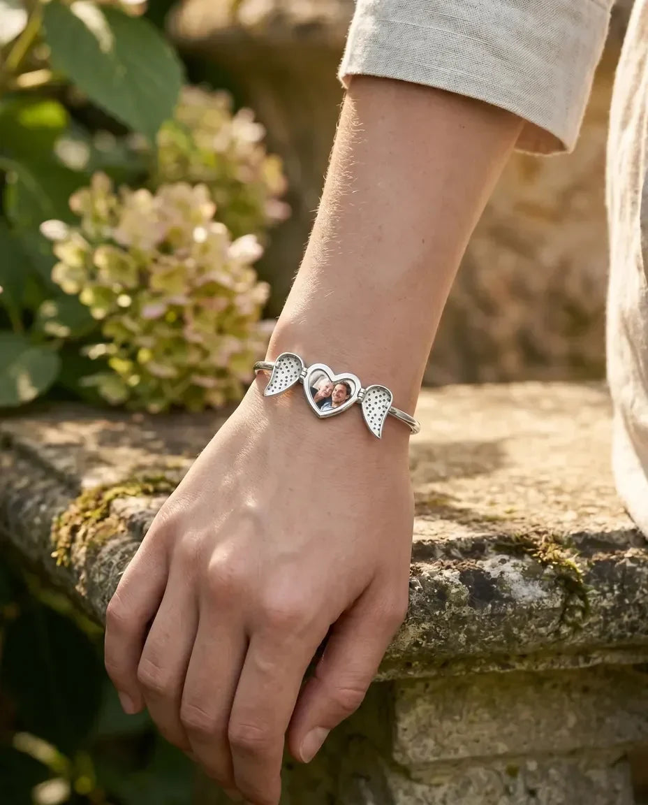 Angel wing heart bangle worn on wrist, close up