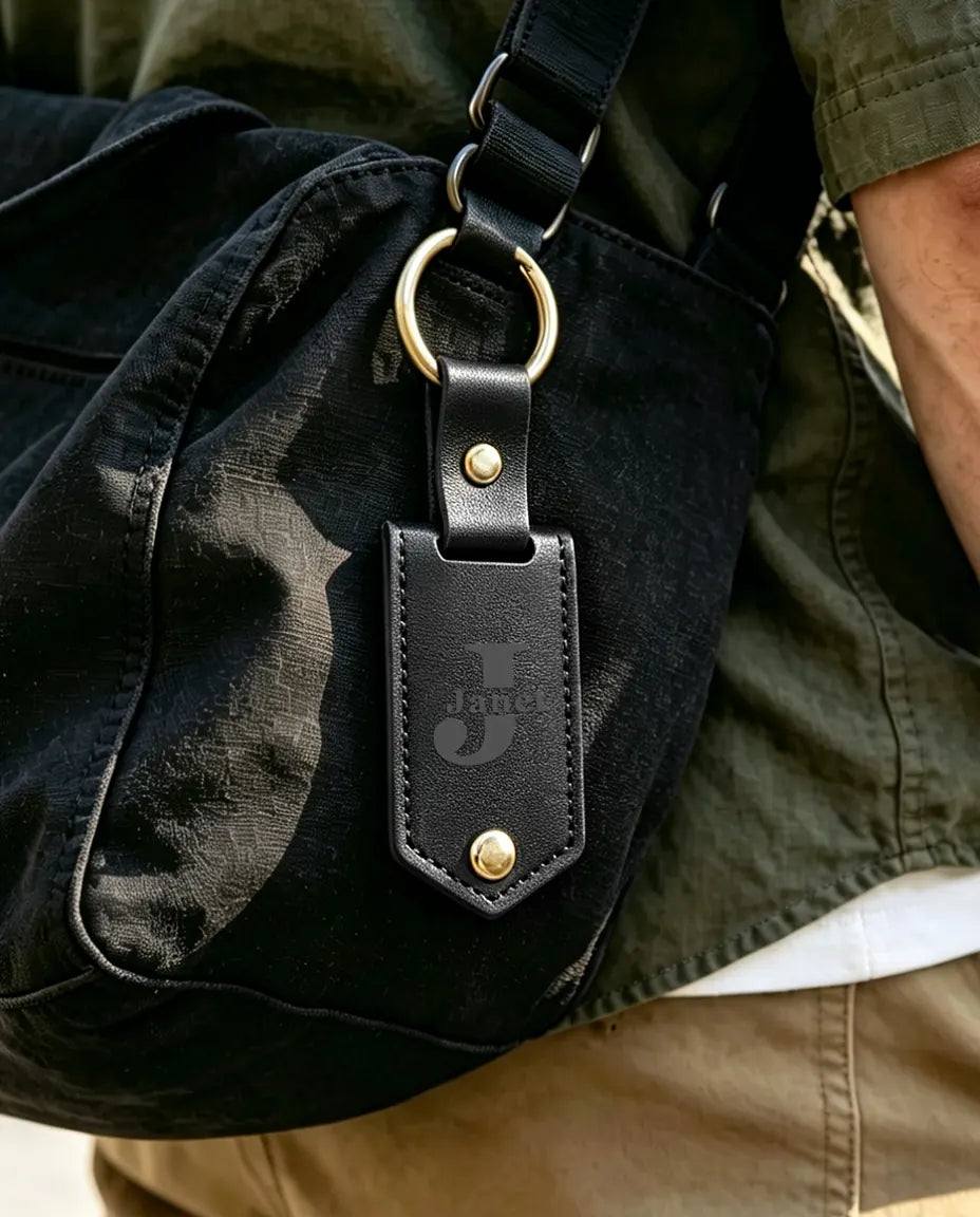 Black engraved faux leather photo keyring clipped to a bag