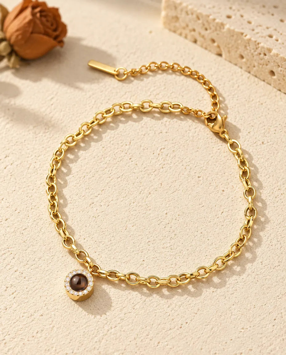 Gold tone pave circle photo projection bracelet resting on cream plaster
