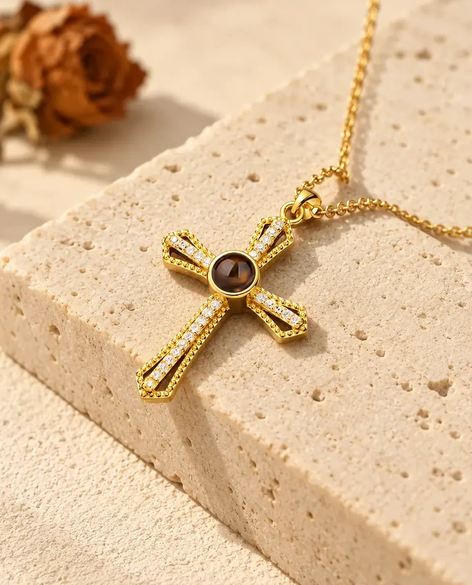 Gold tone open frame cross with a row of cubic zirconia resting on a travertine block