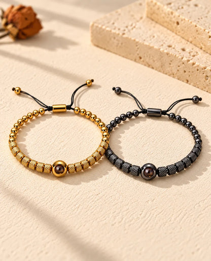 Personalised couples photo projection bracelets, a matching set of two textured bead bracelets in gold tone and black on cream plaster