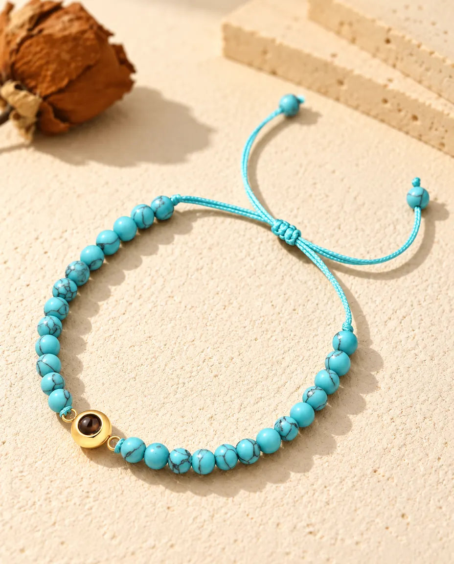 Personalised photo projection bead bracelet with blue marbled beads and a gold tone ring charm on cream plaster