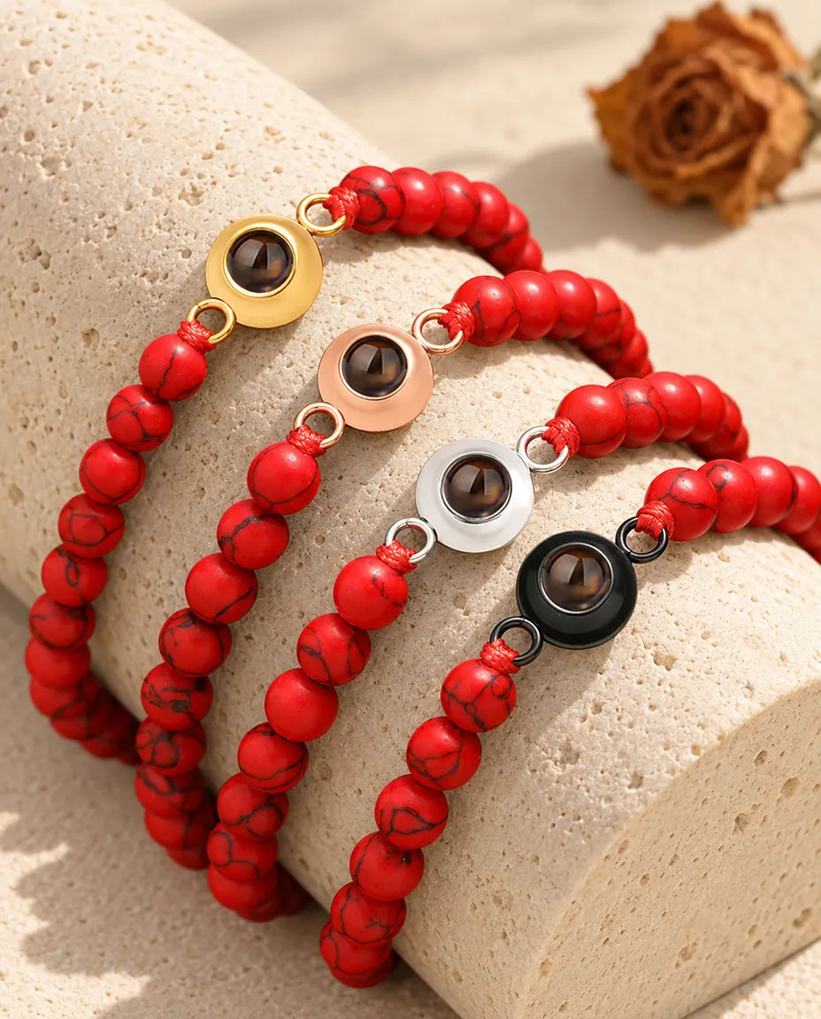 Red marbled bead projection bracelets in four charm colours on a travertine block