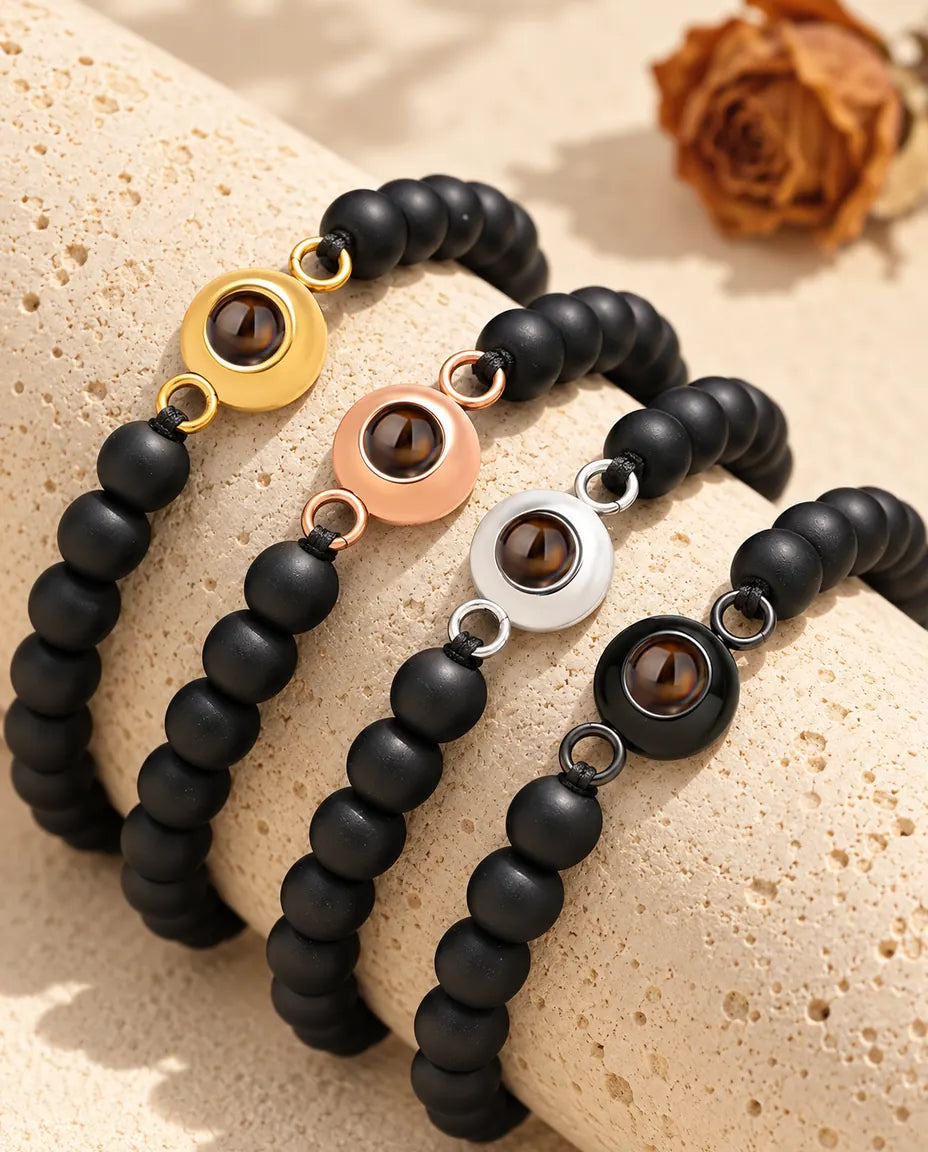 Matte black bead projection bracelets in each charm colour draped over travertine