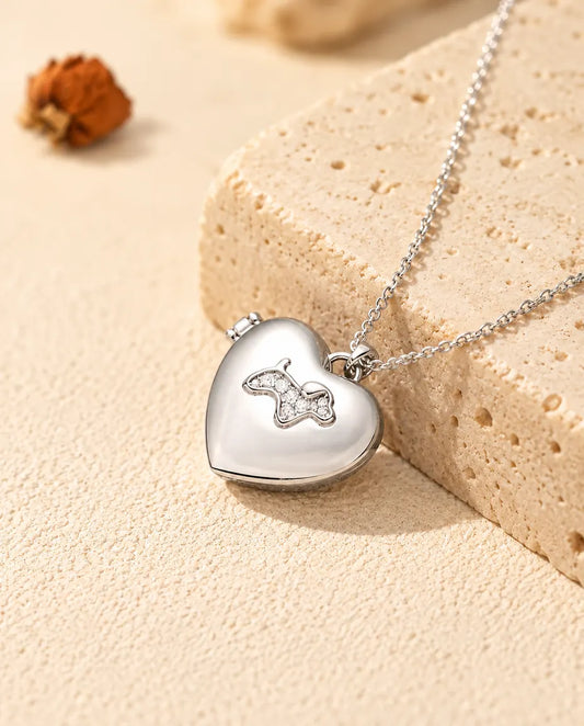 Personalised puppy heart photo locket necklace in silver tone with a cubic zirconia puppy on the lid, resting on a travertine block