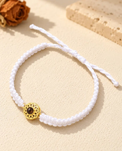 White braided cord photo projection bracelet with a gold tone round charm and sliding knot closure