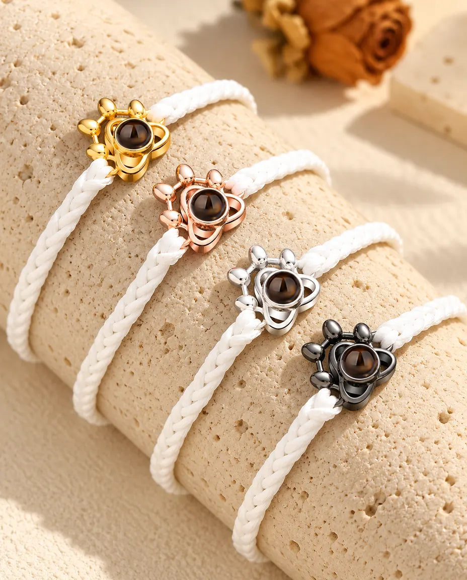 White braided cord paw charm bracelets lined up in each charm colour