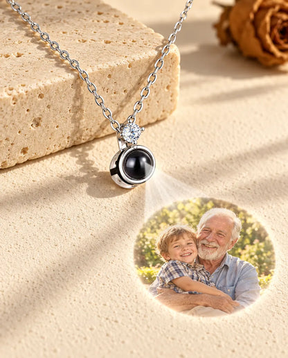 Silver tone solitaire necklace projecting a grandfather and grandson photo onto plaster