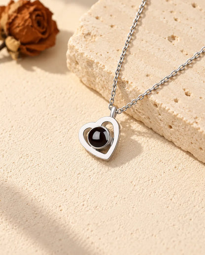 Personalised 925 sterling silver double heart photo projection necklace on cream plaster beside travertine