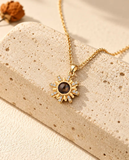 Personalised gold tone sunburst photo projection necklace on a travertine block