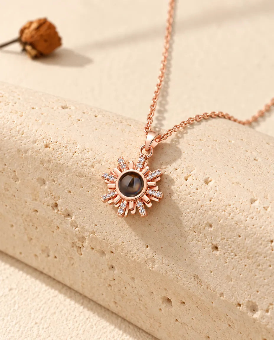 Rose gold tone sunburst projection necklace hanging over travertine