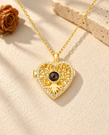 Front view of the gold tone tree of life heart locket with the projection stone at the centre