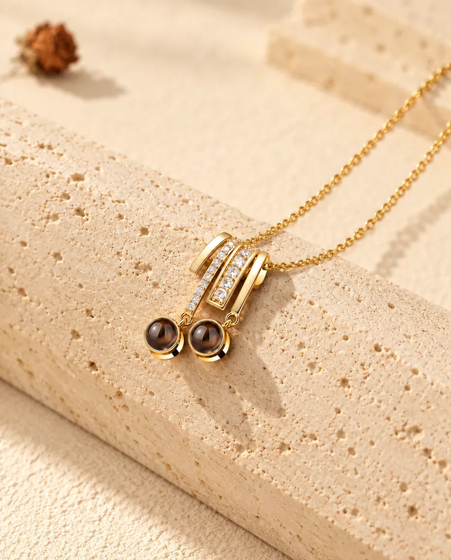 Gold tone pave slide necklace with two round projection stones resting on travertine