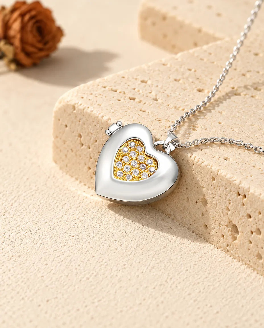 Personalised two-tone pave heart photo locket necklace in silver tone with a gold tone pave inner heart, resting on a travertine block