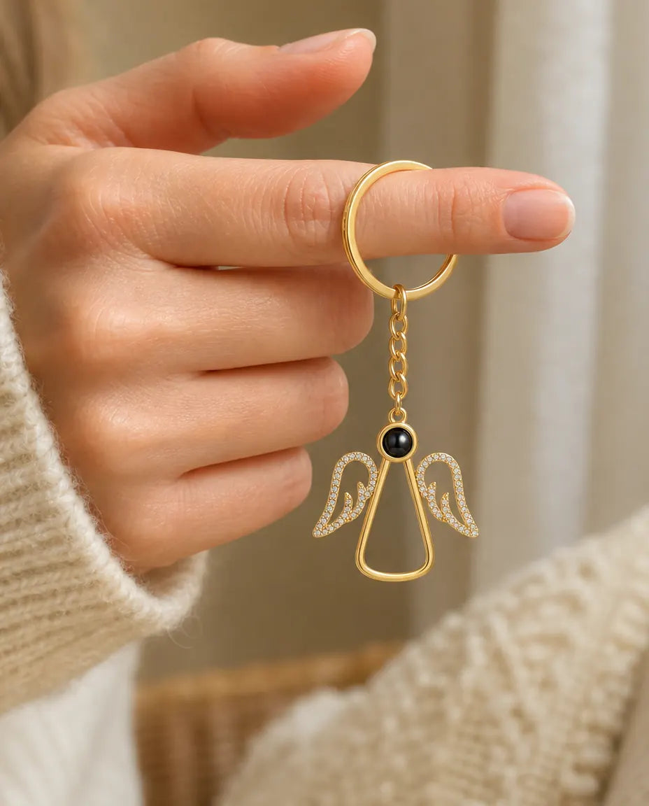Woman holding the gold angel photo projection keyring by its split ring