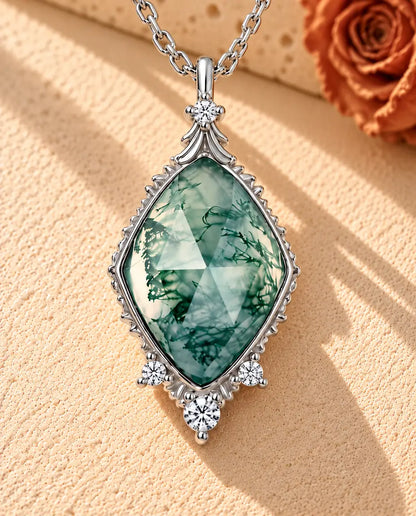 Rose Cut Moss Agate Lozenge Necklace in 925 Sterling Silver - lying on a cream textured surface beside a travertine block