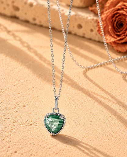 Heart Moss Agate Pendant Necklace in 925 Sterling Silver - seen at an angle on a cream textured surface