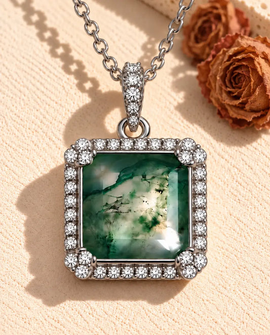 Square Moss Agate Halo Necklace in 925 Sterling Silver - lying on a cream textured surface beside a travertine block