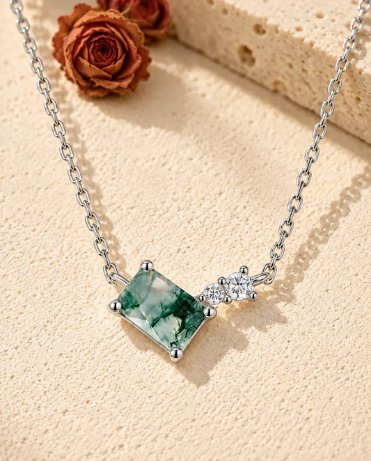 Moss Agate Bar Necklace in 925 Sterling Silver - lying on a cream textured surface beside a travertine block