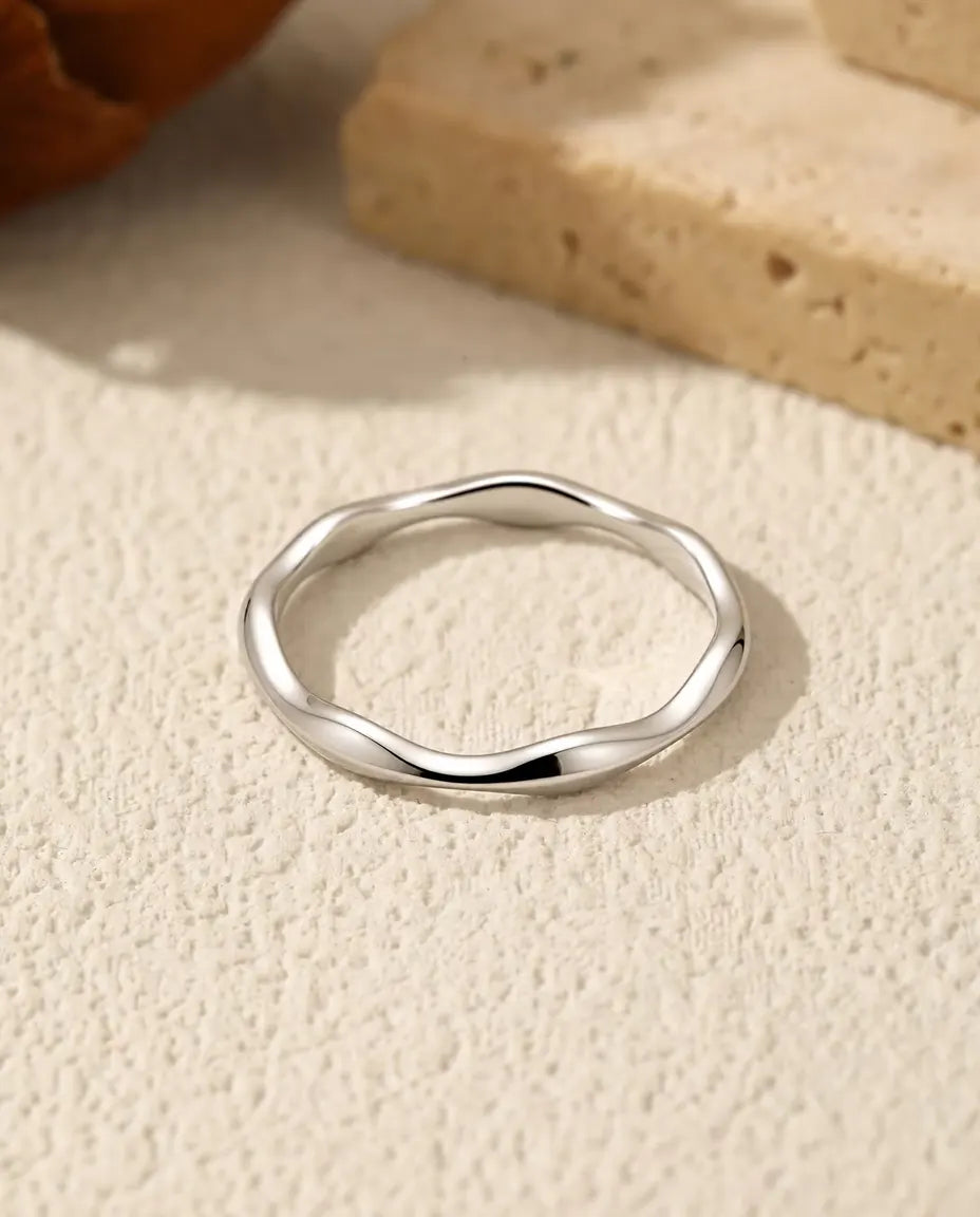 Wavy Band Ring in 925 Sterling Silver - lying flat on a cream textured surface